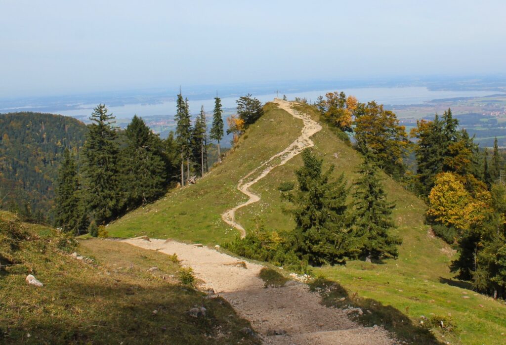 Ein Bergweg, der sich durch die Landschaft schlängelt und in der Ferne zu einem Kreuz führt – Symbol für Orientierung, Zielstrebigkeit und innere Stärke.